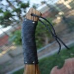 Close-up of the Viking axe handle, made from polished wood with a black braided leather grip for a secure hold